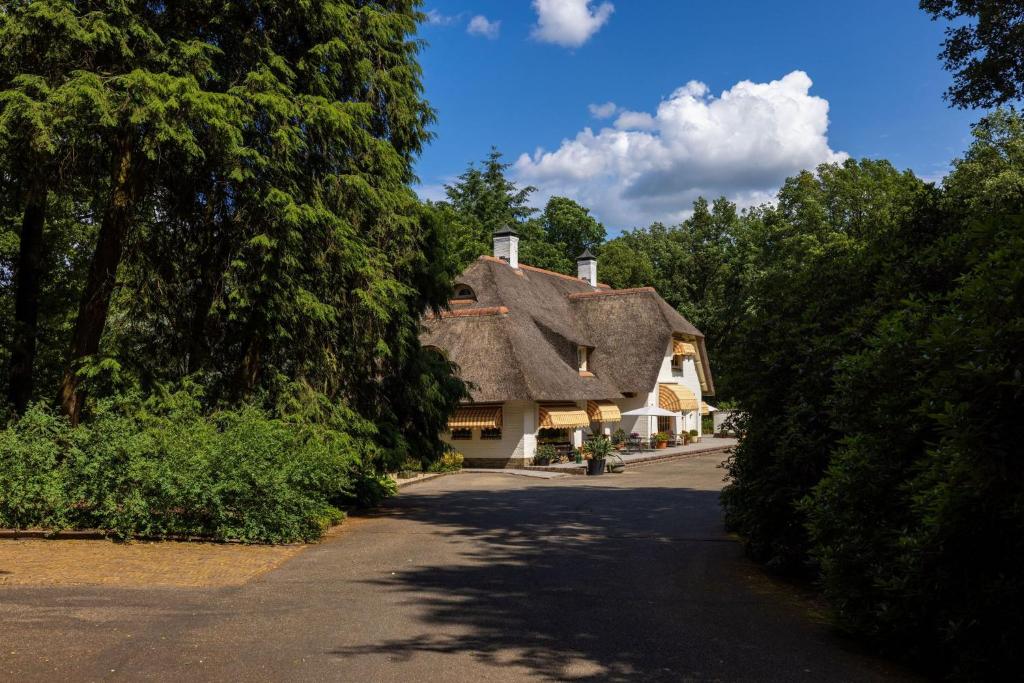 贝克贝亨Vakantiehuisje op de Veluwe!的茅草屋顶和车道的房子