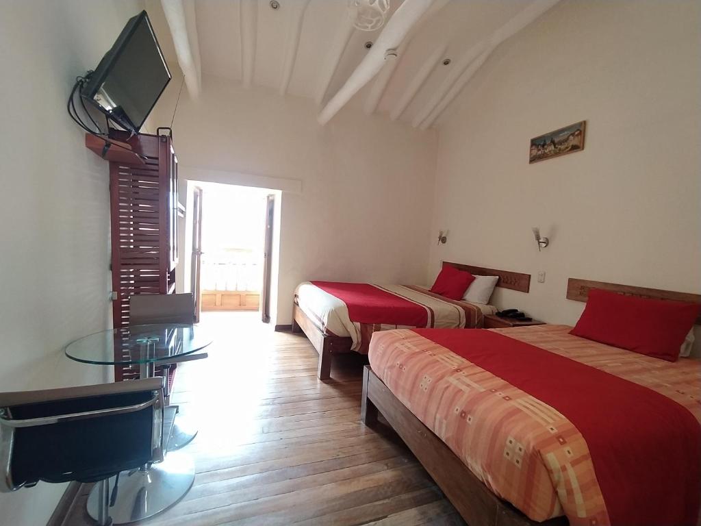 库斯科麦特酒店的客房设有两张床和一台墙上的电视。