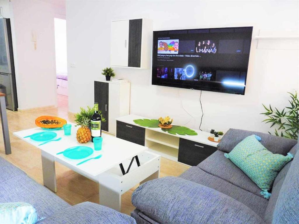 圣伊西德罗Vacaciones Sur Tenerife Ofogar的带沙发、桌子和电视的客厅