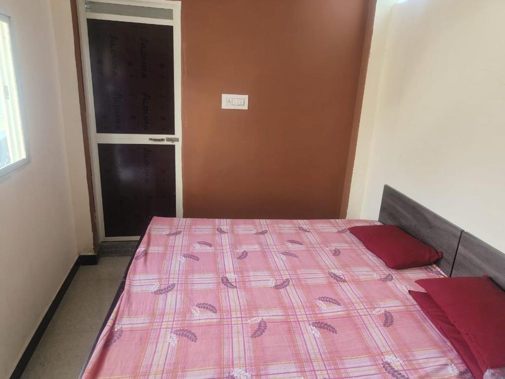 乌贾因Kailash kuti Guest House的一间卧室配有一张带粉红色棉被的床
