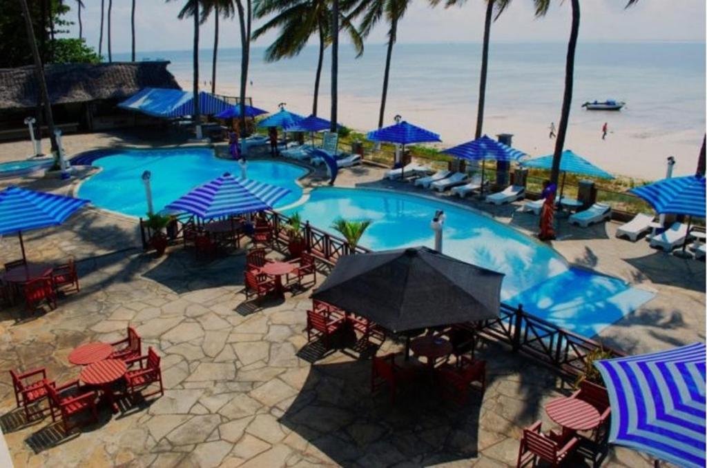 班布里Sai Rock Beach Hotel & Spa的一个带桌椅和蓝伞的大型游泳池