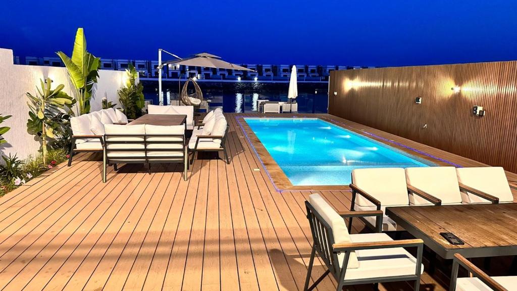 富查伊拉Luxury Villa 5 bedrooms with sea view and free boat的一个带椅子的甲板和晚上的游泳池