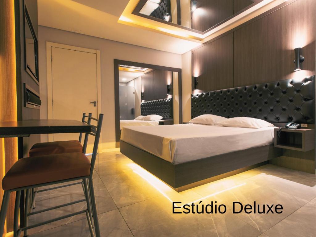 帕罗卡Drops Palhoça Motel的卧室配有1张床、1张桌子和1把椅子