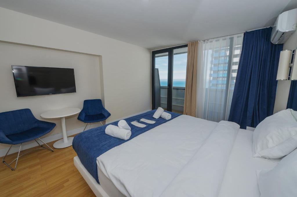 巴统Twin Towers Orbi City Batumi的一间卧室配有一张带蓝色椅子的大床和电视