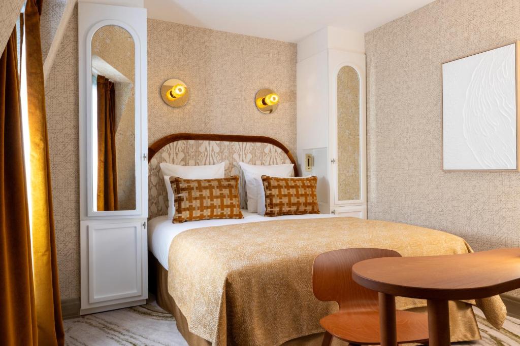 巴黎Hotel des Carmes by Malone的酒店客房配有一张床铺和一张桌子。