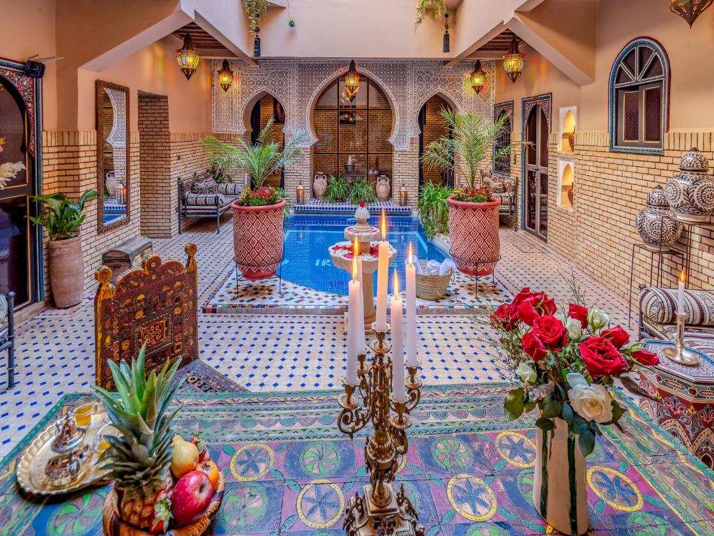 马拉喀什翼哈里娜摩洛哥传统庭院住宅的庭院设有鲜花桌和游泳池