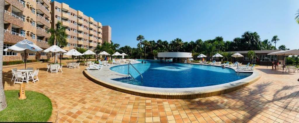 巴雷里尼亚斯Hotel- Gran lençóis flat 408的一个带白色椅子和遮阳伞的大型游泳池