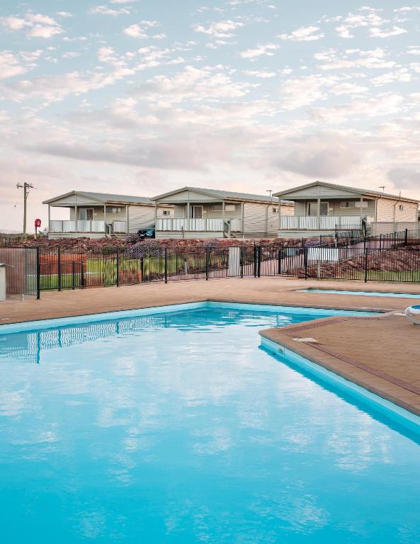 卡尔巴里Kalbarri Red Bluff Tourist Park的大楼前的蓝色海水游泳池