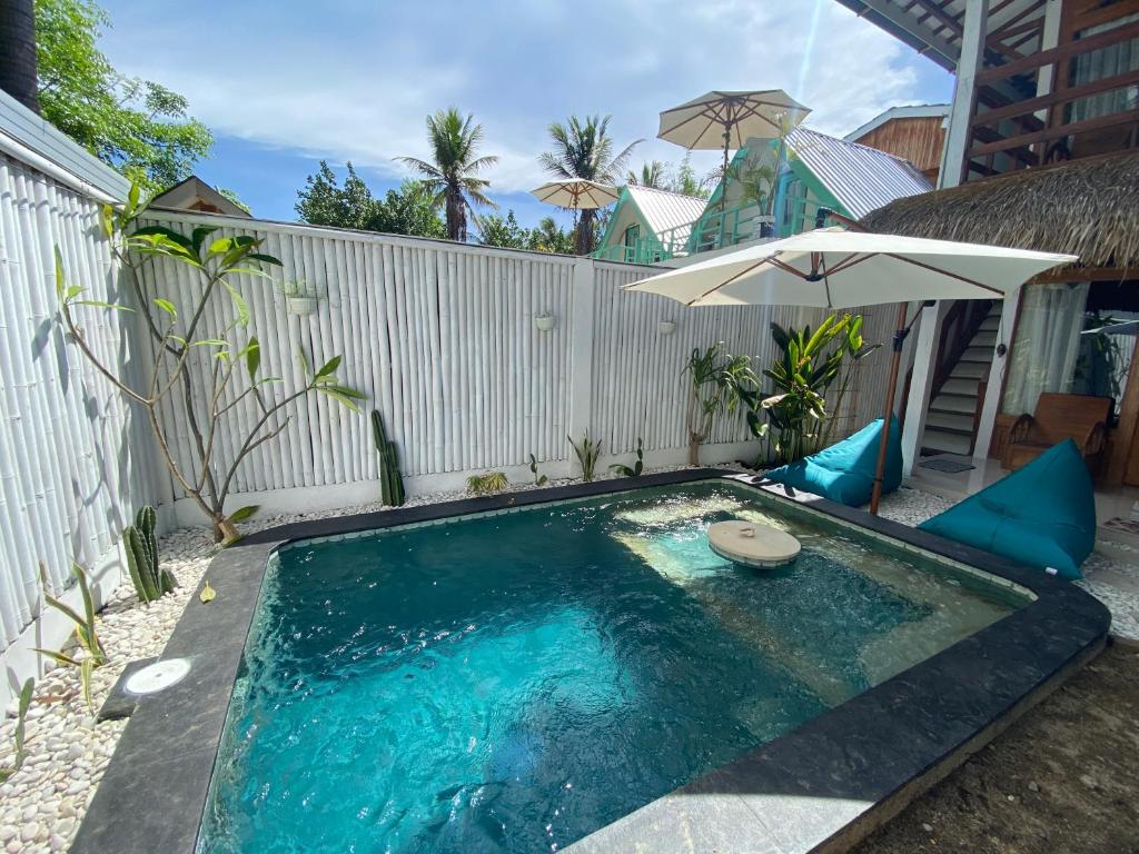 吉利特拉旺安Rascal House Gili Trawangan的一个带遮阳伞和前厅的小型游泳池