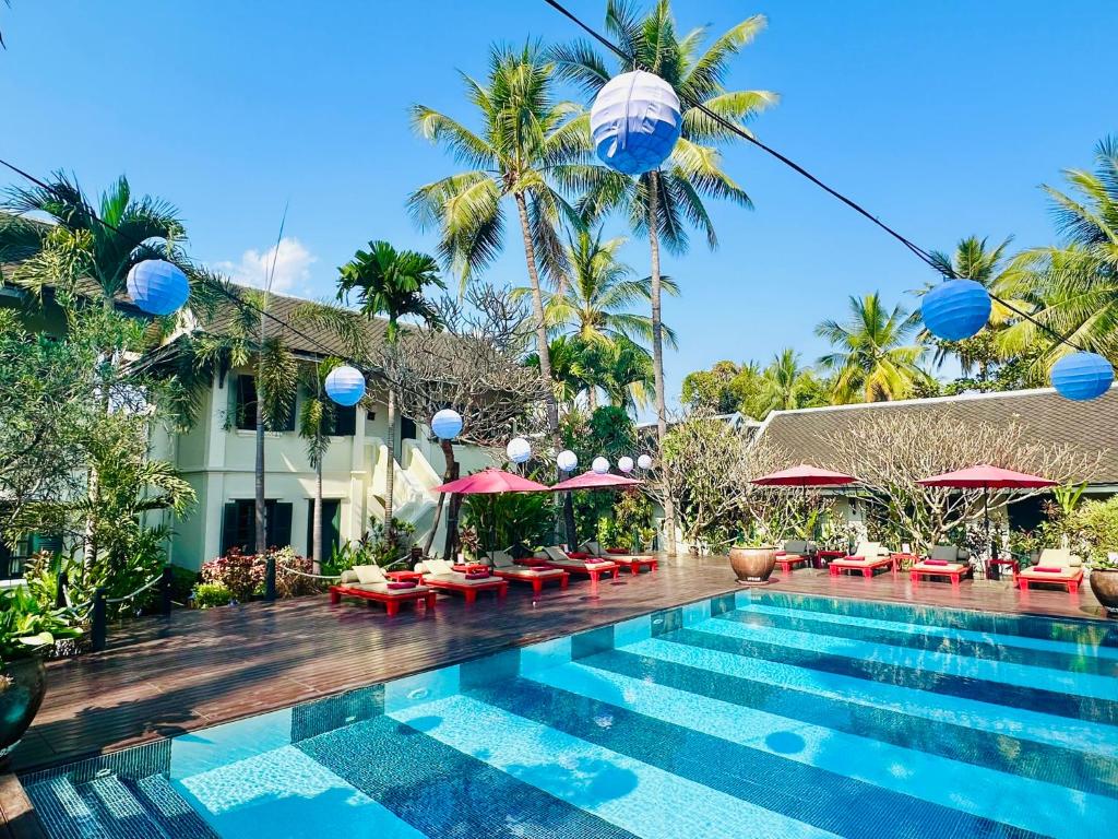 琅勃拉邦玛丽别墅精品酒店的棕榈树和遮阳伞度假村的游泳池