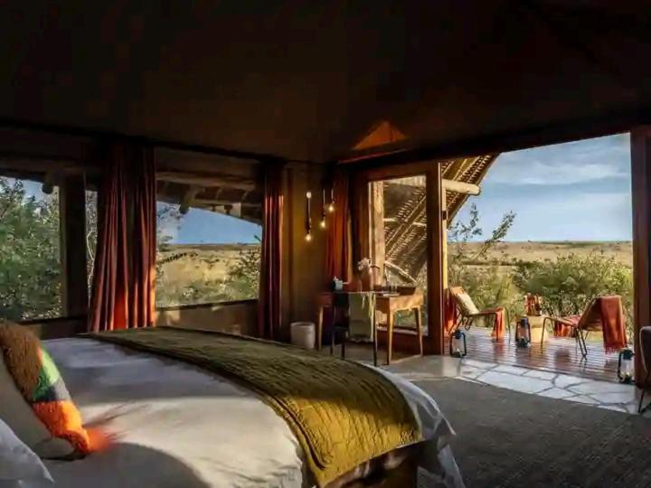 Sekenanisunrise mara safari camp的一间卧室配有一张床,享有田野美景