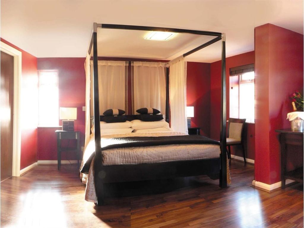 巴尔内特Nap Inn Savoro的一间卧室配有一张带红色墙壁的天蓬床