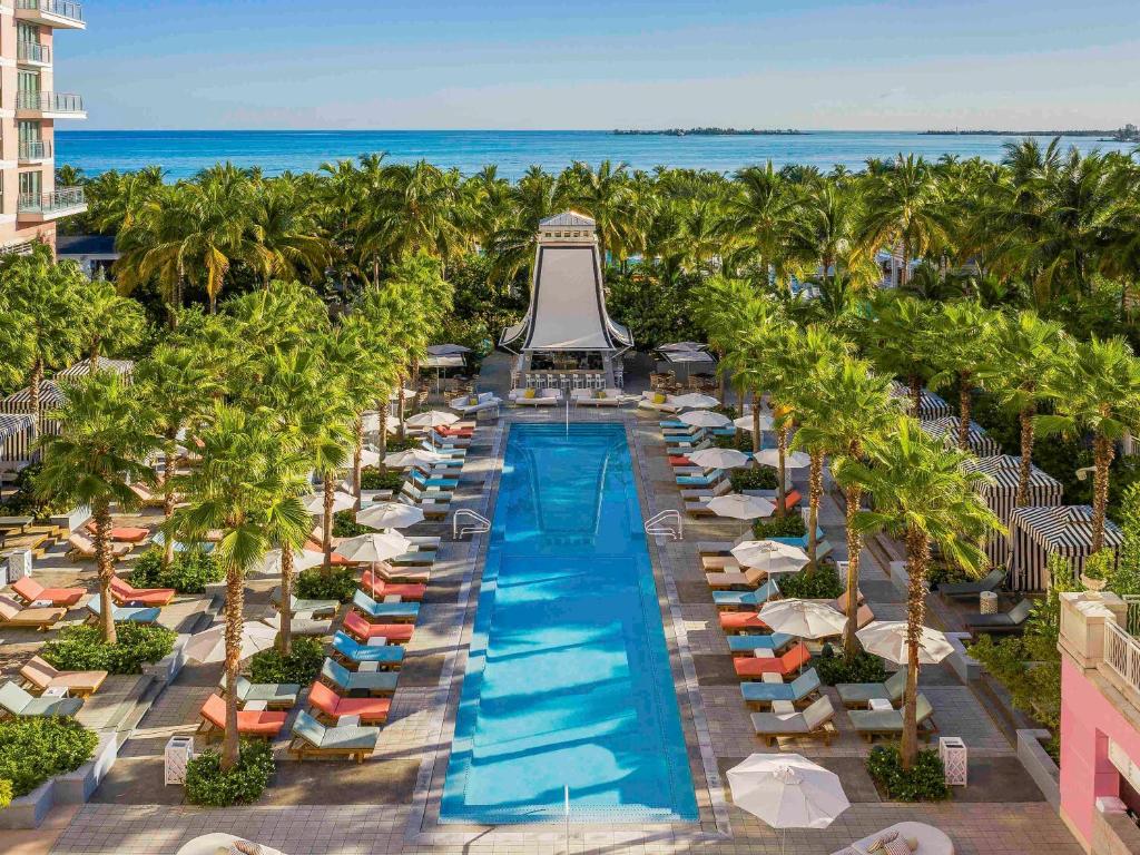 拿骚巴哈玛SLS酒店的享有带椅子和棕榈树的度假村游泳池的空中景致
