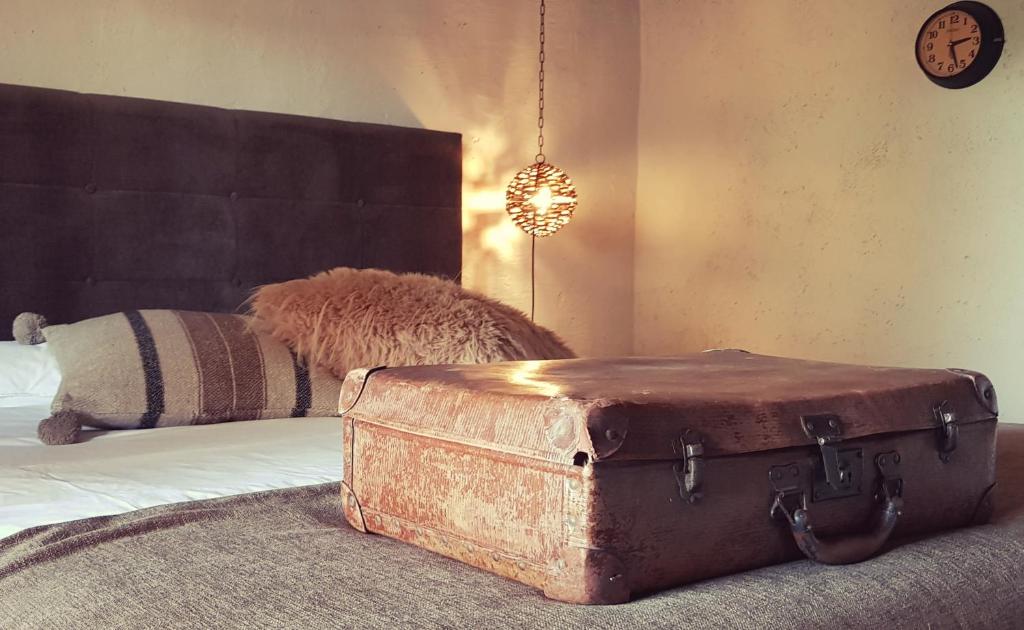 维尔雅尔姆Le Lodge des Flâneurs的卧室里一张床上的旧行李箱