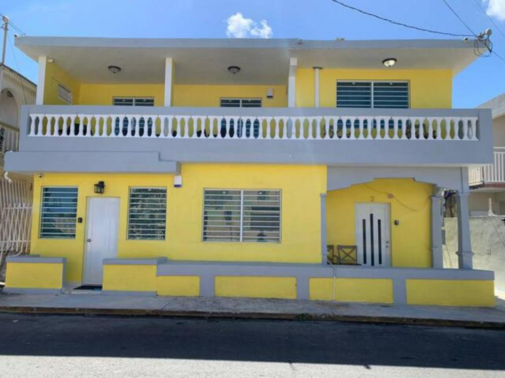 CatanoChic 3 Bedroom Unit, Few Steps To The Ocean, Barbosa Unit 4的黄色房子的顶部设有阳台