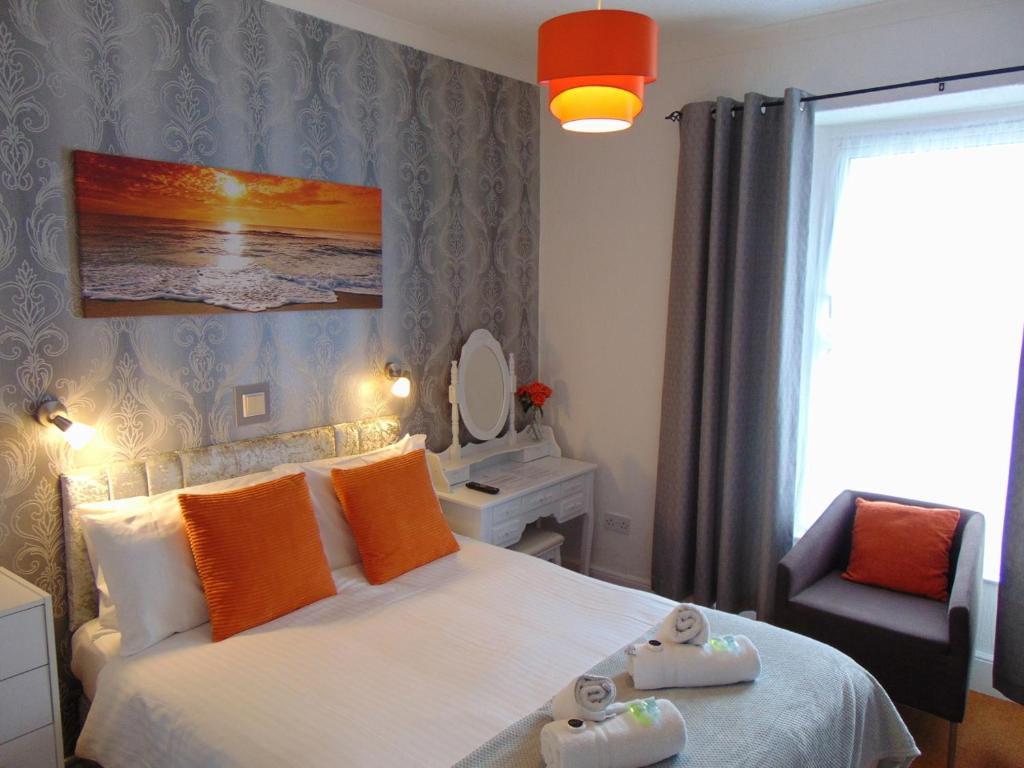 佩恩顿Seacroft Guest House的一间卧室配有带橙色枕头和椅子的床