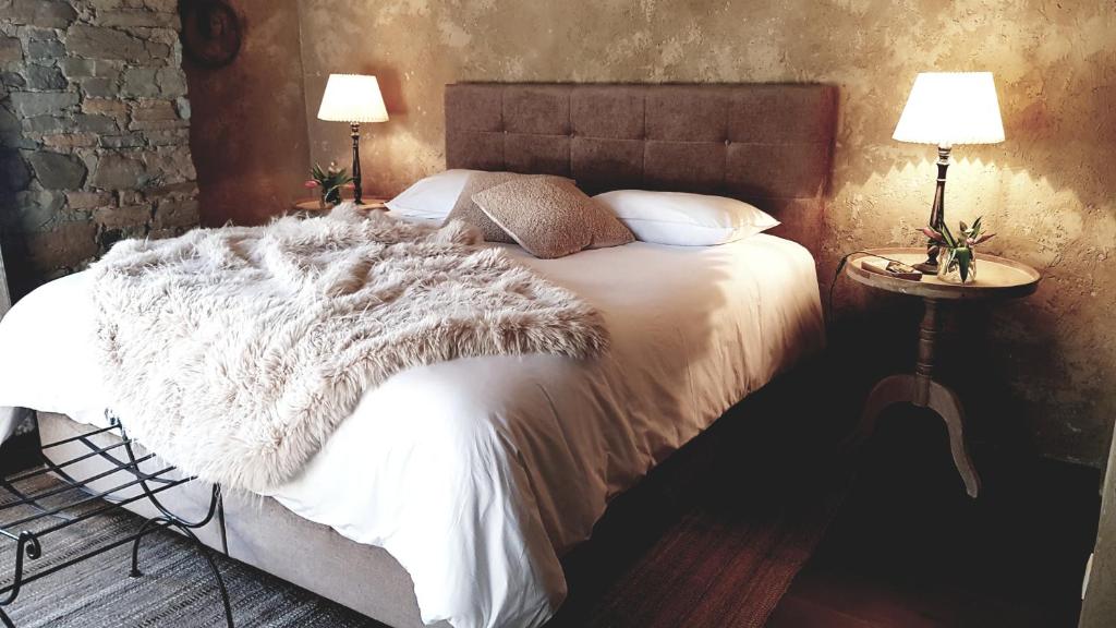 维尔雅尔姆Le Lodge des Flâneurs的一间卧室配有一张带白色毯子和两盏灯的床。