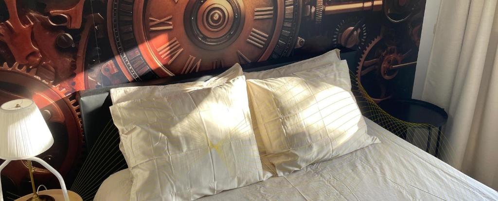 埃因霍温BnB Goldies的一张带两个枕头的床,床后面是时钟