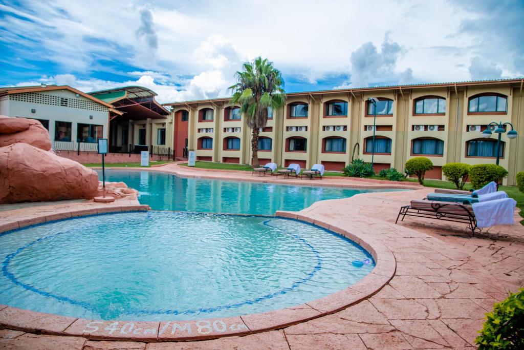 卢萨卡M'kango Golfview Hotel的一座大型建筑,在一座建筑前设有一个游泳池