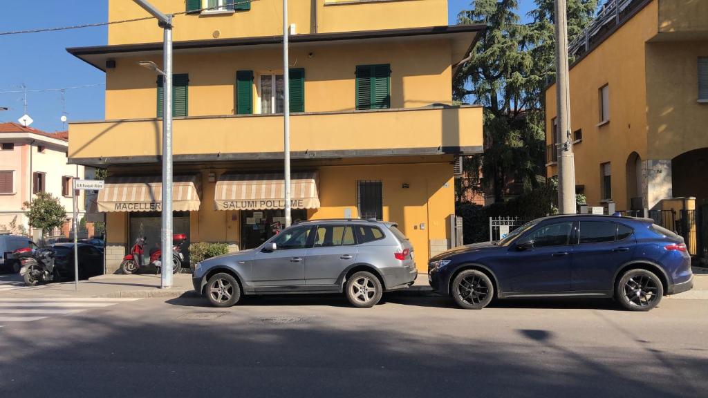 博洛尼亚Casa Francia Emilia Levante的两辆汽车停在大楼前的街道上