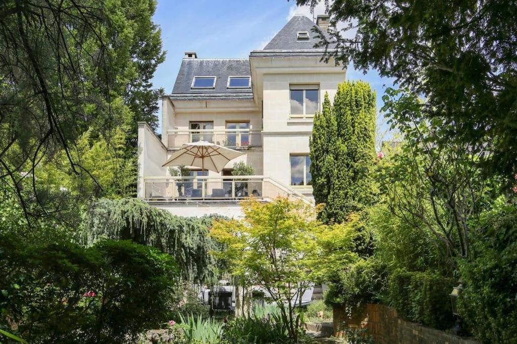 丰特奈苏布瓦Villa des Oliviers的花园中带遮阳伞的大型白色房屋