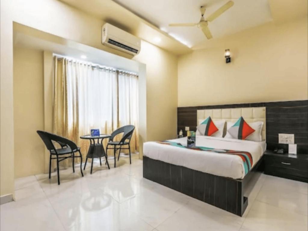 孟买HOTEL V.G的卧室配有一张床和一张桌子及椅子