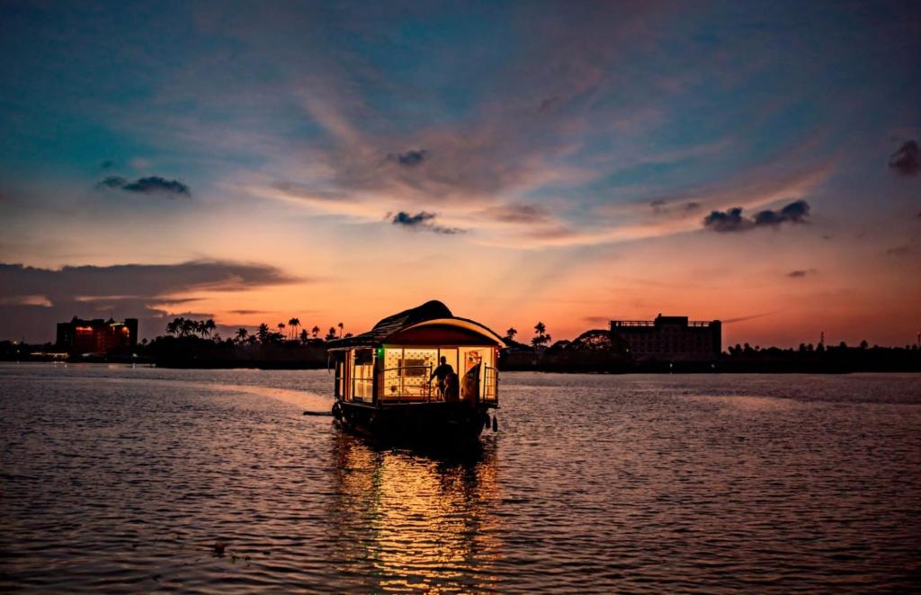 阿勒皮Alice Houseboats Alleppey的日落时分在水中的小船