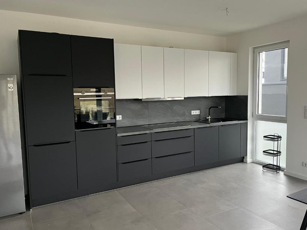 多特蒙德Luxus Neubauwohnung mit Blick auf den Phönix-See的厨房配有白色橱柜和黑色冰箱。