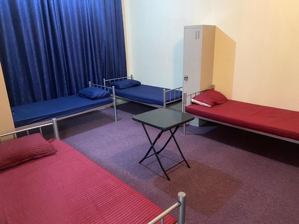 阿布扎比Dream valley hostel的配有蓝色窗帘和桌子的三张床