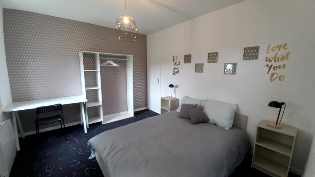 第戎Adorable studio avec entrée indépendante的一间卧室配有一张床、一张书桌和一个窗户。