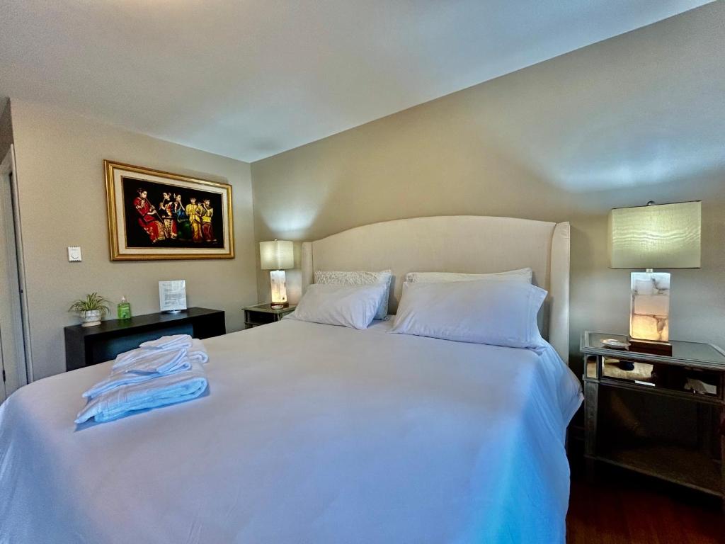 纳奈莫North Nanaimo Gem - Garden-View Room with Private Ensuite的一间卧室配有一张带两盏灯的大型白色床。