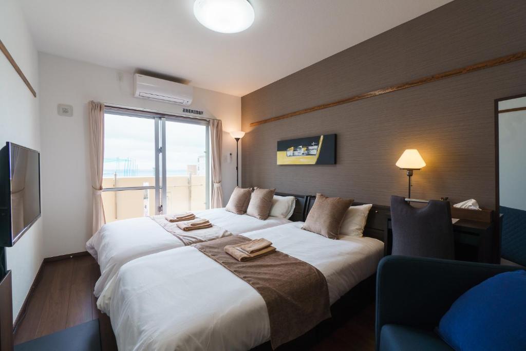 那霸KINTARO Hotel Okinawa Naha的一间设有大床和窗户的酒店客房