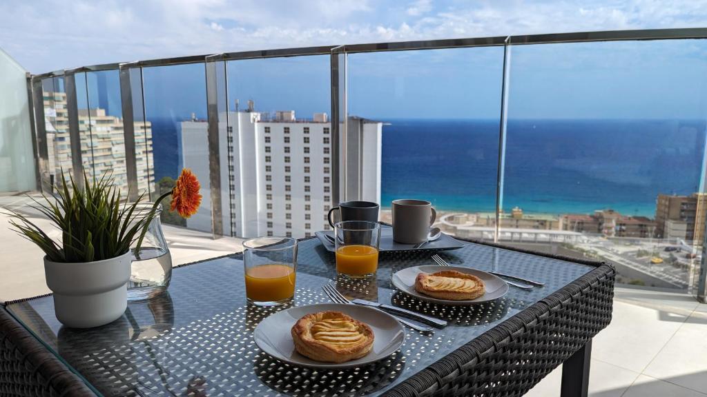 贝尼多姆SUNSET WAVES sea view apartments的一张桌子,上面放着两盘食物和两杯橙汁