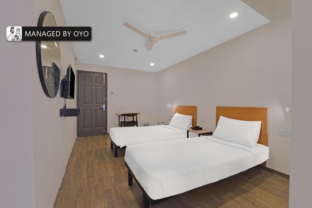 钦奈Super Townhouse OMR Laxmi Nagar的配有白色床单的客房内的两张床