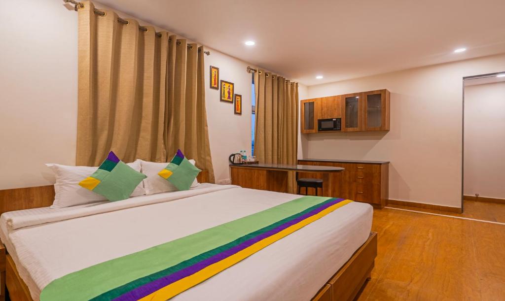 海得拉巴Treebo Trend SY Inn - Gachibowli DLF的卧室配有一张带彩色枕头的大型白色床。