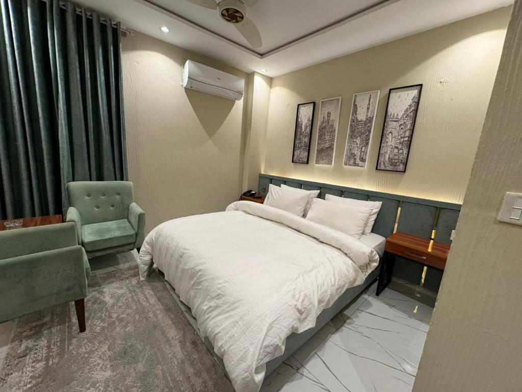拉合尔Shelton Boulevard Hotel Lahore的配有一张床和一把椅子的酒店客房