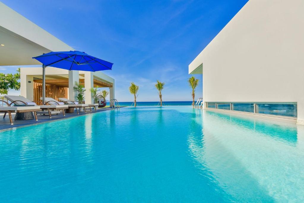 岘港Danang Amazing Ocean Villas的一个带椅子和遮阳伞的无边泳池