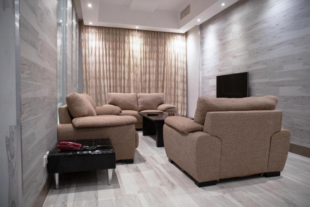 科威特Terrace Furnished Apartments Fintas 2的客厅配有两把椅子和电视