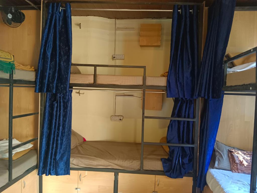 孟买Victory dormitory的带3张双层床和蓝色窗帘的房间