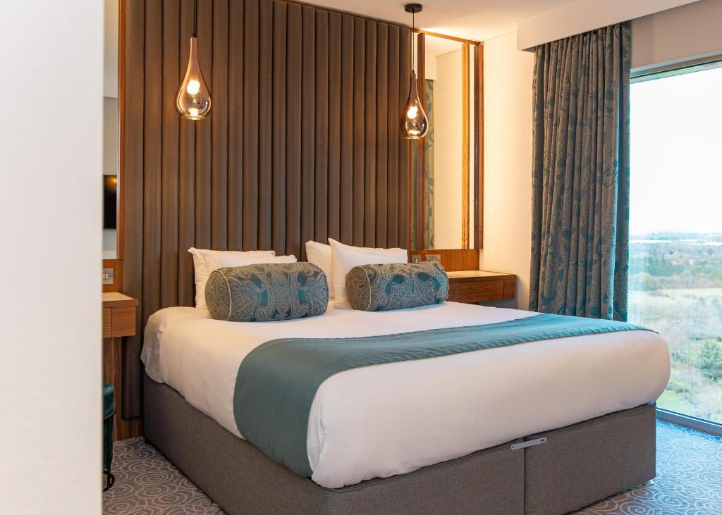 米尔顿凯恩斯Hotel La Tour的一间卧室设有一张大床和大窗户