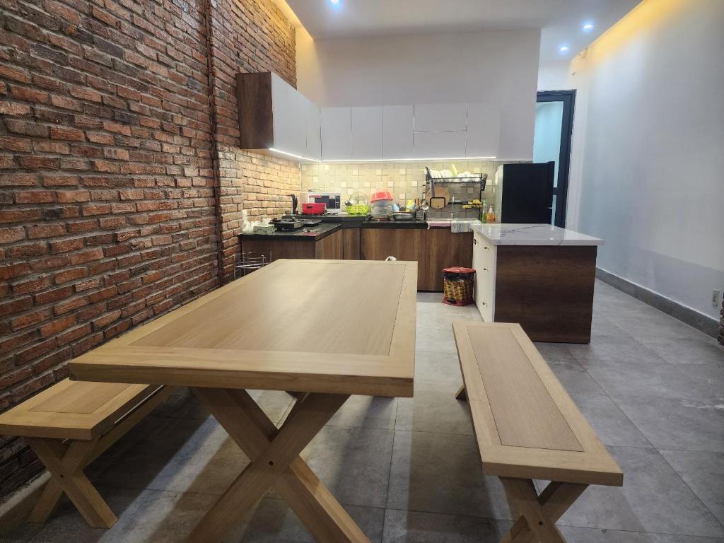 芹苴T-House的厨房配有木桌和砖墙
