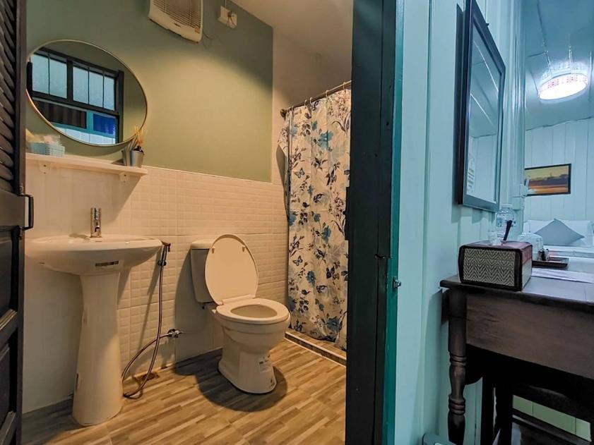 That PhanomSangthong Heritage hotel โรงแรมแสงทองเฮอริเทจ的一间带卫生间、水槽和镜子的浴室