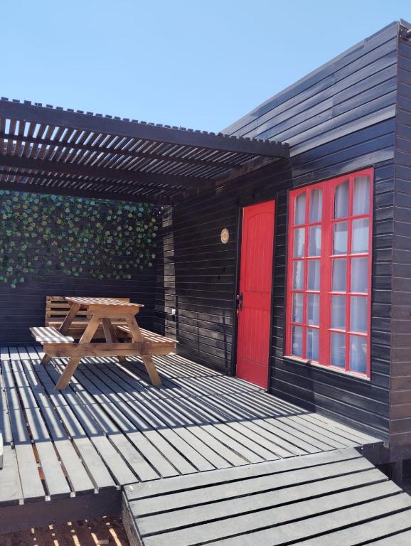 科金博Cabañas Guayacanes的木甲板,配有野餐桌和红色的门