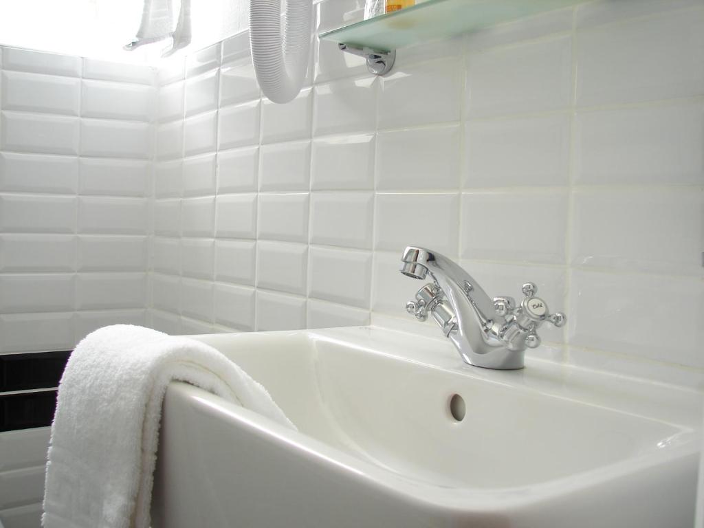 勒芒夏尔乐敦酒店的白色的浴室设有水槽和白色毛巾