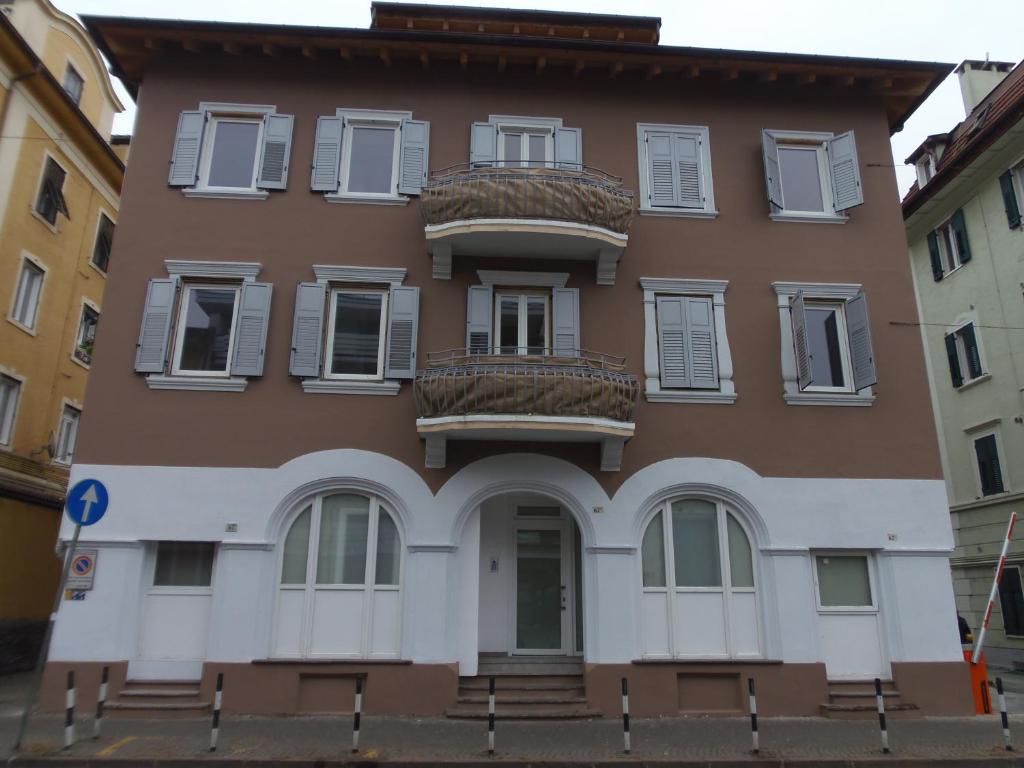 博尔扎诺Apartaments Claudia Augusta的棕色的建筑,设有白色的窗户和楼梯
