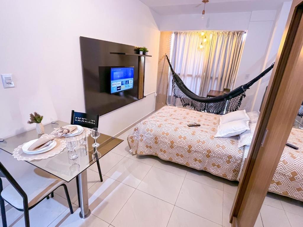 大坎皮纳Ap standard confort bem localizado的一间卧室配有吊床、一张桌子和一台电视。