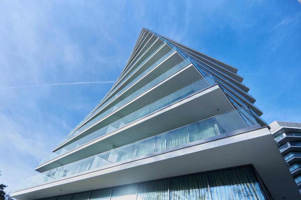 米兹多洛杰Wave De Luxe Studio Resort&SPA 755B - Sea View的一座高大的玻璃建筑,背后是蓝天