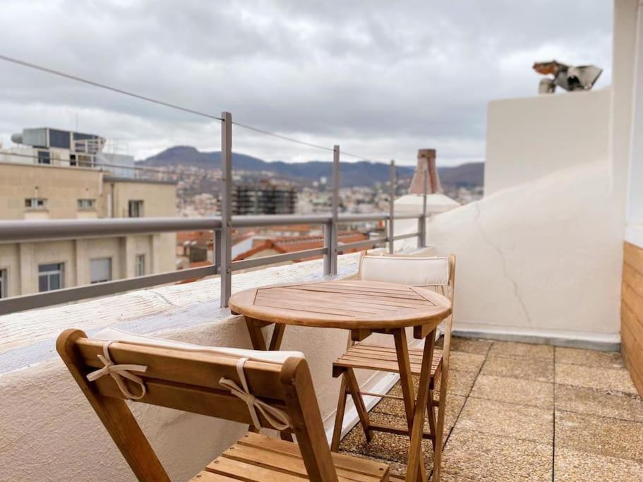 克莱蒙费朗DUPLEX - TERRASSE 2 CHAMBRES CENTRE-VILLE JAUDE的阳台上配有一张木桌和两把椅子