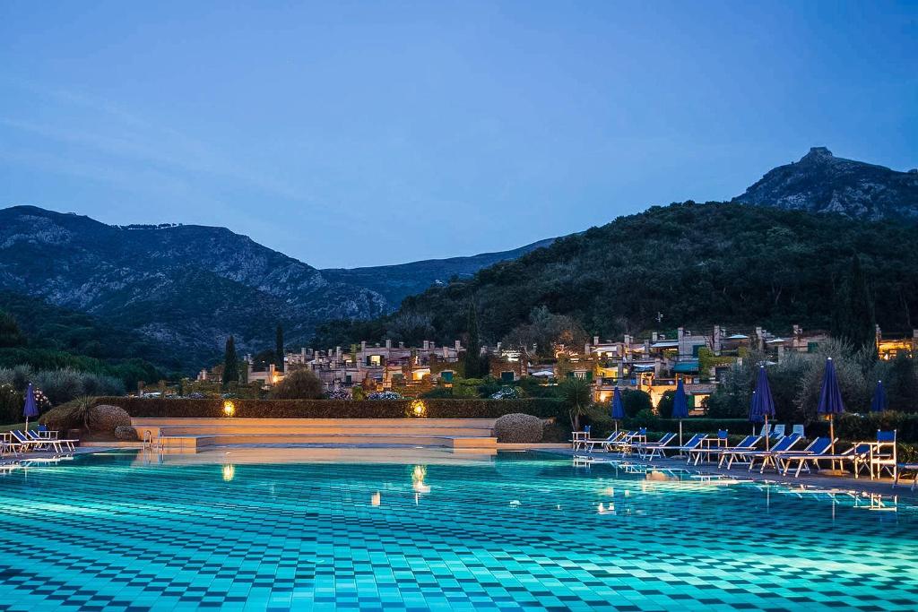 BagnaiaSUITE ELEVEN ISOLA D'ELBA的一个带椅子的游泳池,一个城市背景