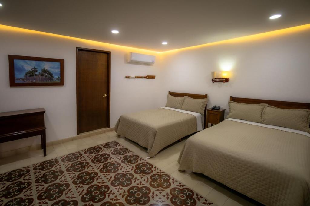 坎佩切航海家旅馆的一间卧室配有两张床、一张桌子和一张地毯。